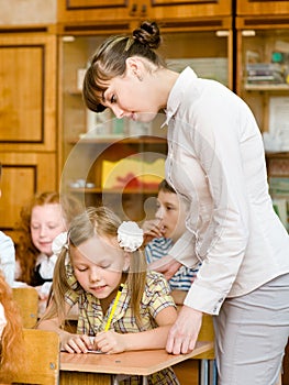 Teacher helps the schoolkids with schoolwork in classroom