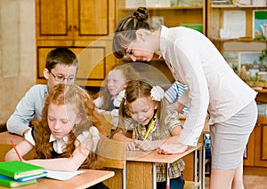 Teacher helps the schoolkids with schoolwork in classroom