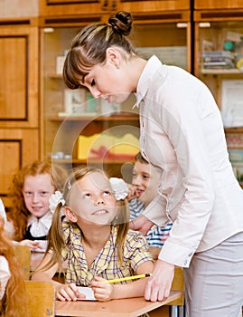 Teacher helps the student with schoolwork in classroom