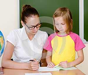 Teacher helps the student with schoolwork in school classroom photo