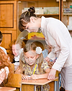 Teacher helps the student with schoolwork in school classroom
