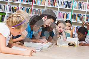 Teacher and kids lying on floor reading book in library