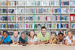 Teacher and kids lying on floor using digital tablet in library