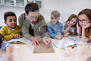 Teacher with kids preparing for chemistry research at school.