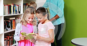 Teacher and kids reading book in library