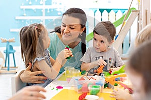 Teacher with children working with plasticine at kindergarten or playschool photo