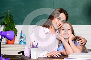 Teacher kind lady with pupil. Doing homework with mom. Little girl and woman sit at desk. School education. Studying