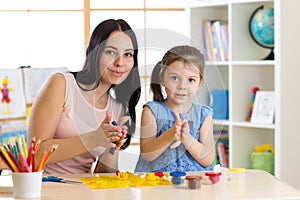 Teacher and little girl child learn mold from plasticine in daycare centre