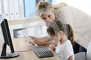 Teacher and little girl using computer and tablet