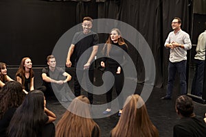 Teacher With Male And Female Drama Students At Performing Arts School In Studio Improvisation Class