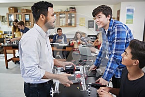 Teacher With Male Pupils Building Robotic Vehicle In Science Lesson