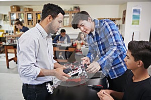 Teacher With Male Pupils Building Robotic Vehicle In Science Lesson