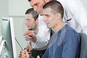 teacher with male students using computers
