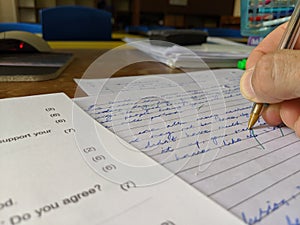 A teacher marking an exam paper at a desk