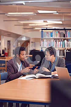 Teacher With Mature Male Adult Student Sitting At Table Working In College Library