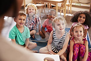 Teacher At Montessori School Reading To Children At Story Time