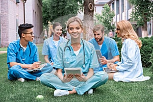 teacher and multicultural students studying outdoors with gadgets