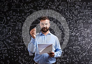 Teacher with notebook against big blackboard with symbols and formulas