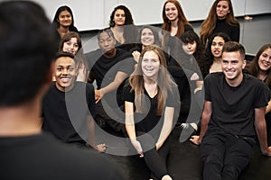 Teacher At Performing Arts School Talking To Students Sitting On Floor In Rehearsal Studio photo