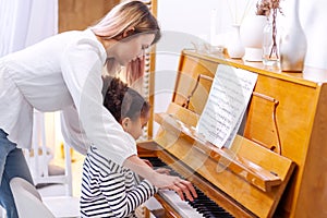Teacher pianist gives piano classes to a young little student