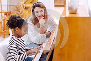 Teacher pianist gives piano classes to a young little student