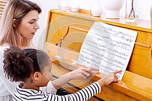 Teacher pianist gives piano classes to a young little student