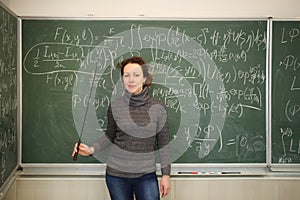 Teacher with pointer stands near blackboard with photo
