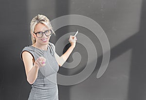 Teacher pointing at camera while writing on blackboard with chalk
