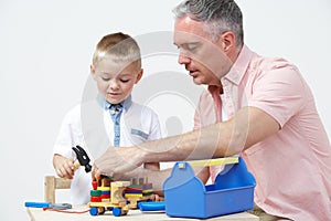 Teacher And Pre School Pupil Playing With Wooden Tools