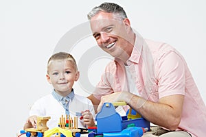 Teacher And Pre School Pupil Playing With Wooden Tools