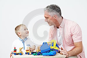 Teacher And Pre School Pupil Playing With Wooden Tools