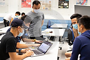 Teacher or professor & College or university Students with face mask & computer have small group teaching and discussio