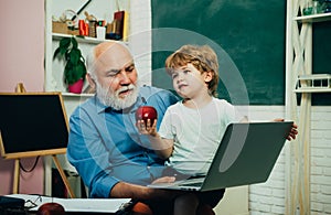 Teacher and pupil learning together in school. Old and Young. Kid with old teacher learning in class on background of