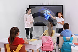 Teacher and pupil using interactive board in classroom during lesson