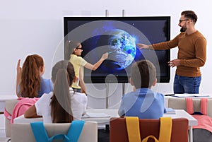 Teacher and pupil using interactive board in classroom during lesson photo