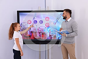 Teacher and pupil using interactive board in classroom during lesson