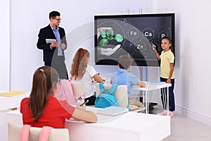 Teacher and pupil using interactive board in classroom during lesson