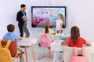 Teacher and pupil using interactive board in classroom during lesson
