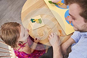 Teacher And Pupil Using Wooden Shapes In Montessori School
