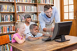 Teacher and pupils using computer at library