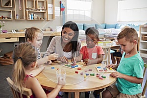 Teacher And Pupils Using Wooden Shapes In Montessori School