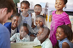 Teacher reading book to elementary school children in class