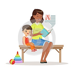 Teacher reading a book to little boy while sitting on a bench, kids education and upbringing in preschool or