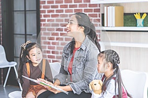 Teacher reading story book to kindergarten students