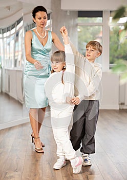 Teacher rearrange dancers pose during pair ballroom dancing lesson.