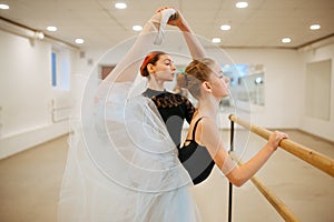 Teacher rehearsing with young ballerina at barre