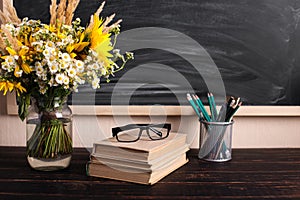 Teacher's day background. Black chalk board empty copy space and fresh wildflowers in vase. Holiday feminine poster.Spring