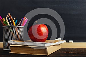 Teacher`s desk with writing materials, a book and an apple, a blank for text or a background for a school theme. Copy space