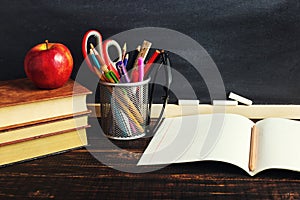 Teacher`s desk with writing materials, a book and an apple, a blank for text or a background for a school theme. Copy space