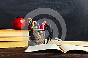 Teacher`s desk with writing materials, a book and an apple, a blank for text or a background for a school theme. Copy space